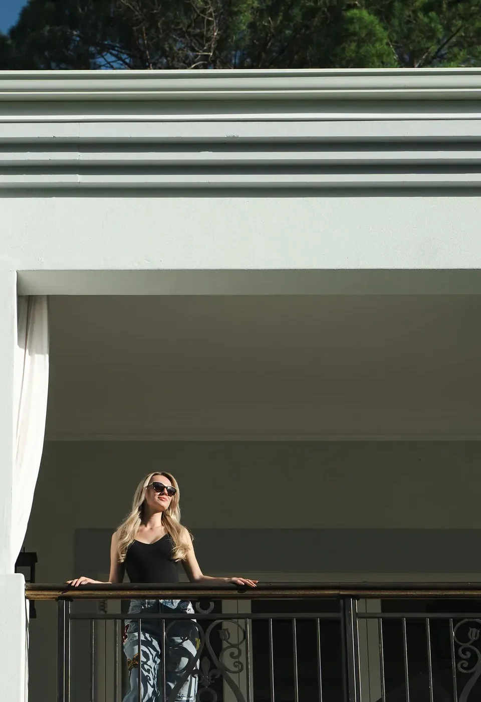 De witte gevel van de villa in Kaapstad, met een builder op het balkon in de zon.